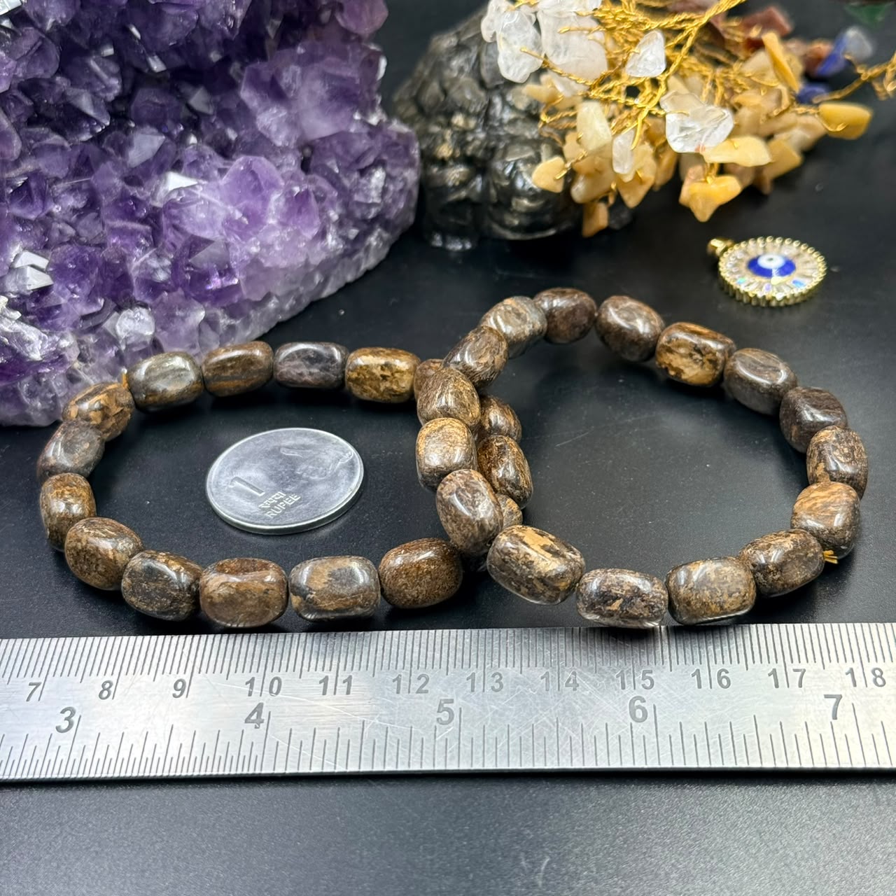 Bronzite tumble bead bracelet on dark stone with ruler for size