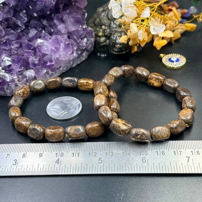 Bronzite tumble bead bracelet on dark stone with ruler for size