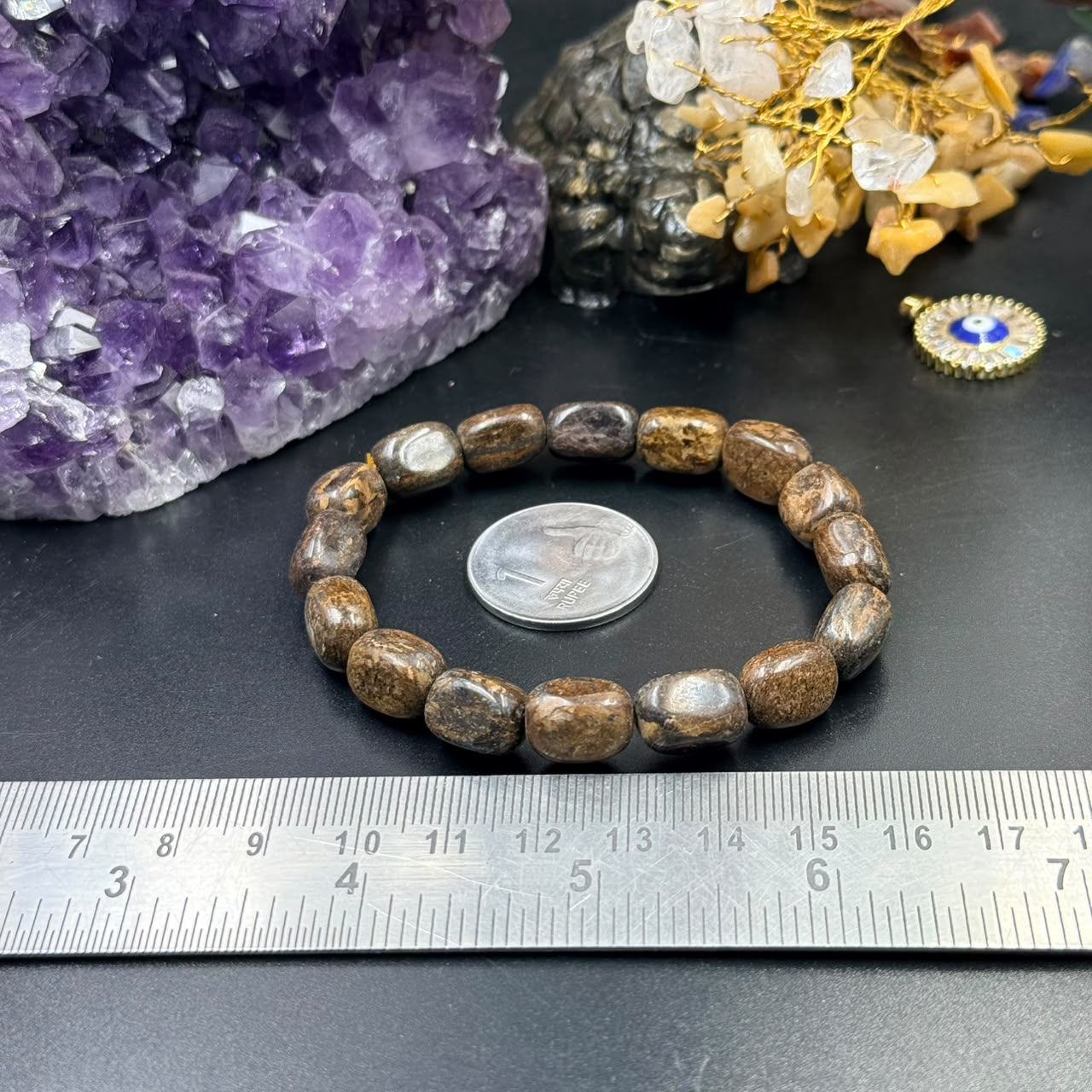 Bronzite tumble bracelet with round beads against amethyst crystal and ruler