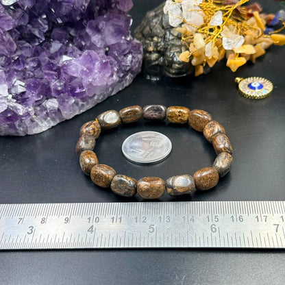 Bronzite tumble bracelet with round beads against amethyst crystal and ruler