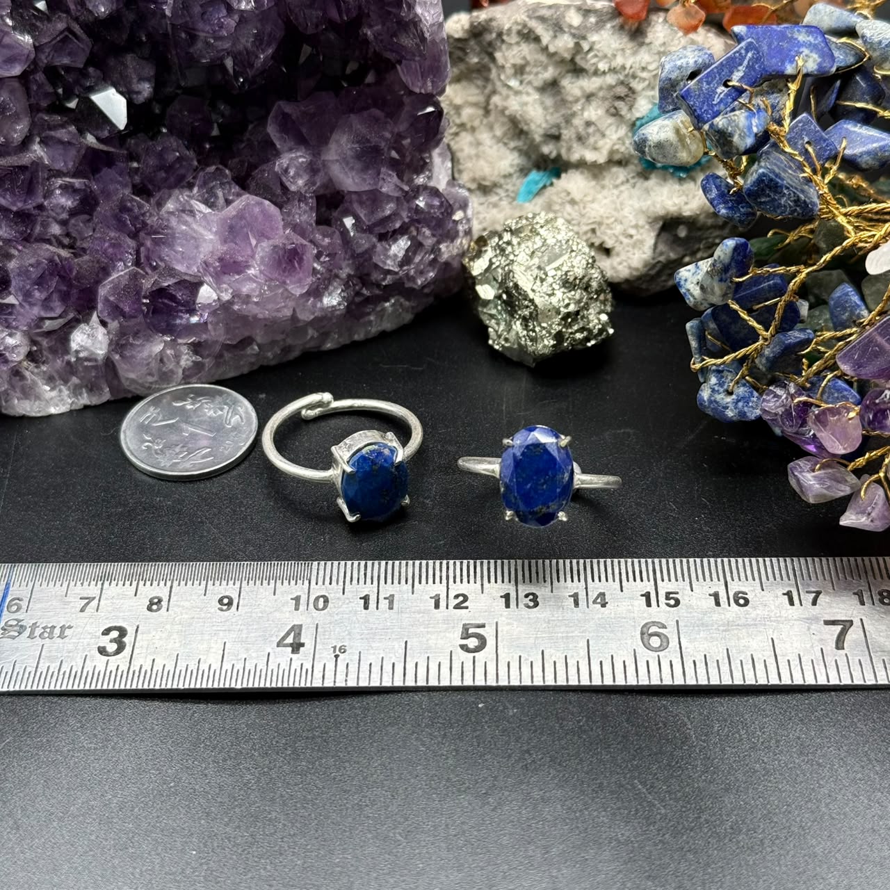 Two adjustable Natural Lapis Lazuli rings with oval blue stones, placed near a coin and ruler.