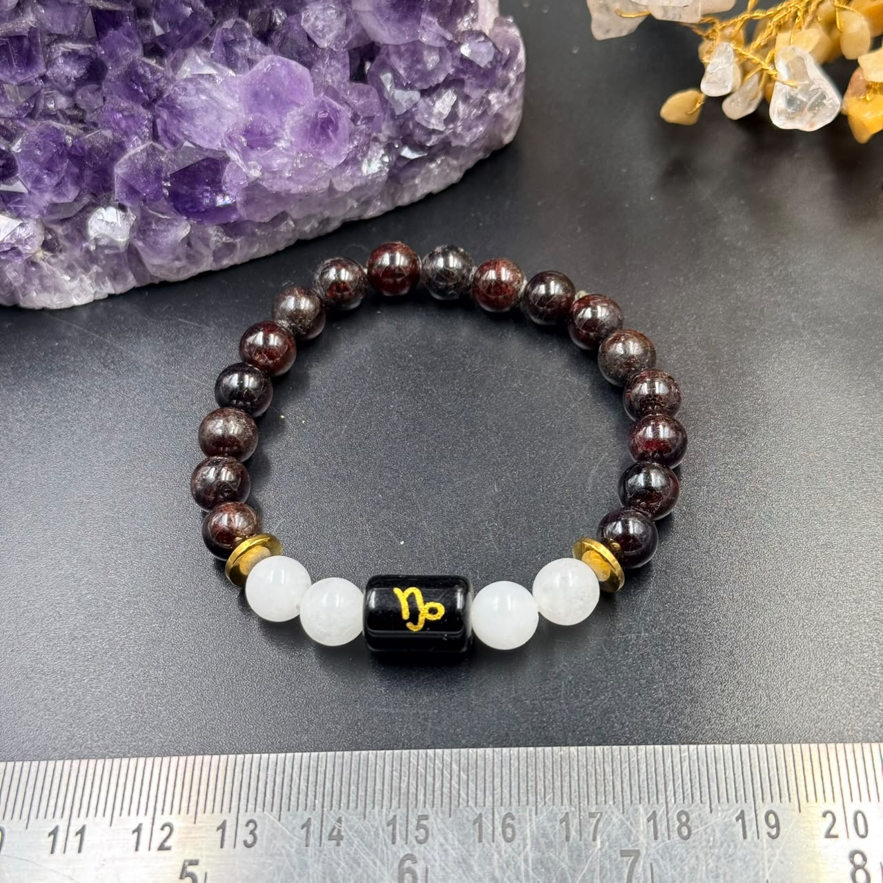 Capricorn zodiac bracelet front view with garnet beads, milky quartz beads and black zodiac charm