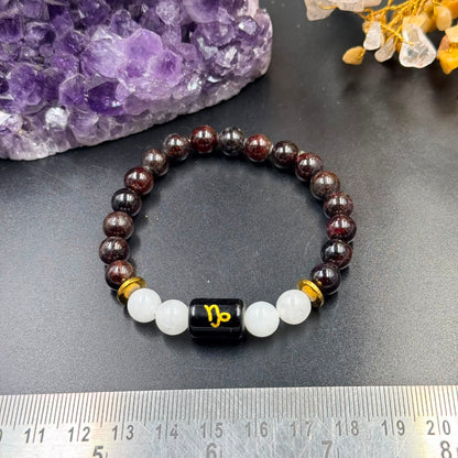 Capricorn zodiac bracelet front view with garnet beads, milky quartz beads and black zodiac charm