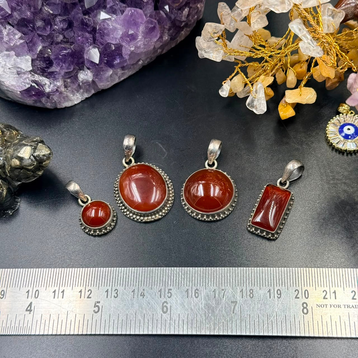Set of carnelian 925 silver locket pendants with red stones in different shapes on black surface