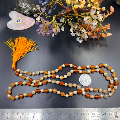 Carnelian 8mm and pearl 6mm Jaap mala with tassel laid out on dark background with crystals