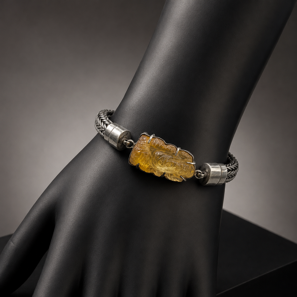 Silver chain bracelet with citrine Ganesha design on a black display stand