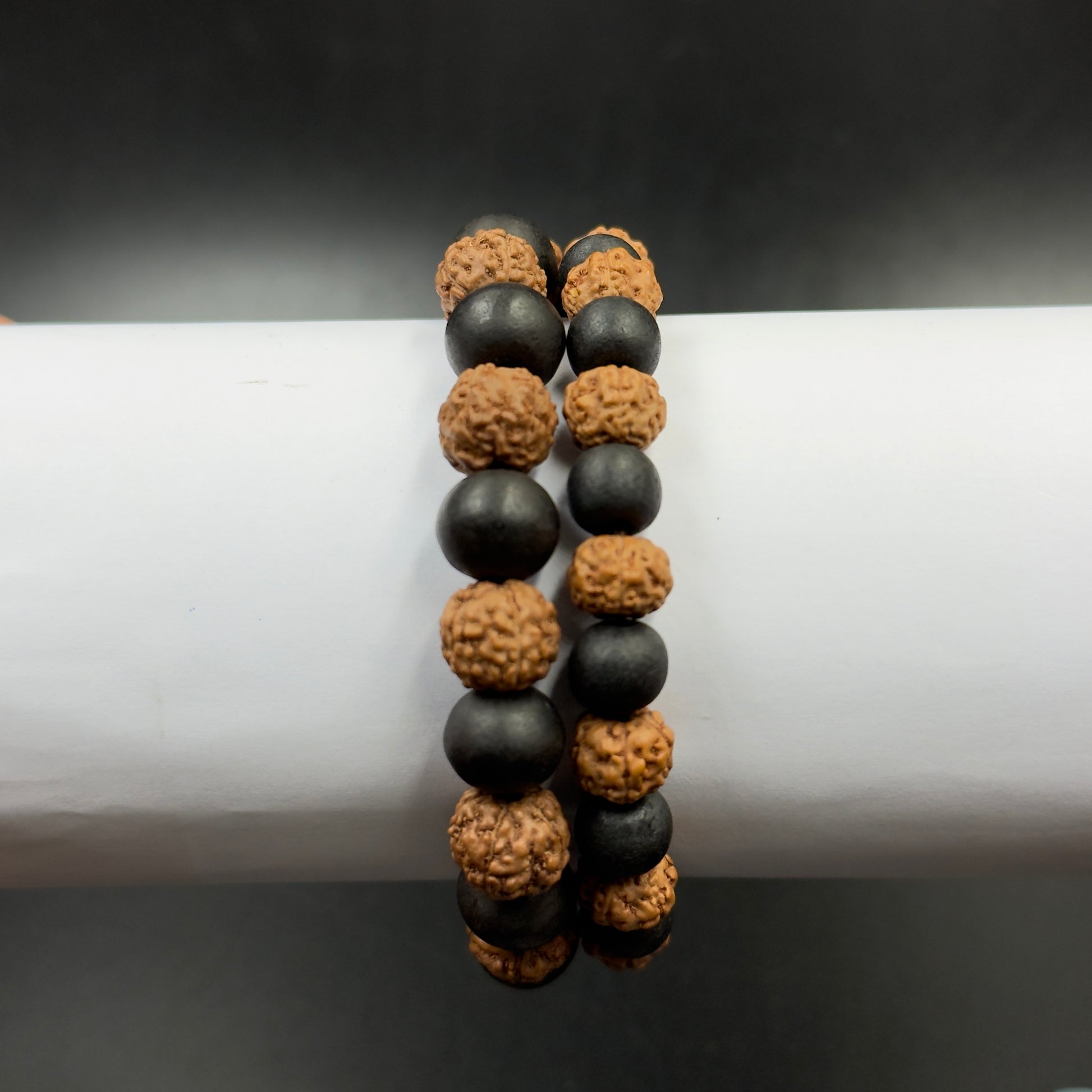 Close-up of a 5 Mukhi rudraksh and karungali bead bracelet showing black beads and tan rudraksh