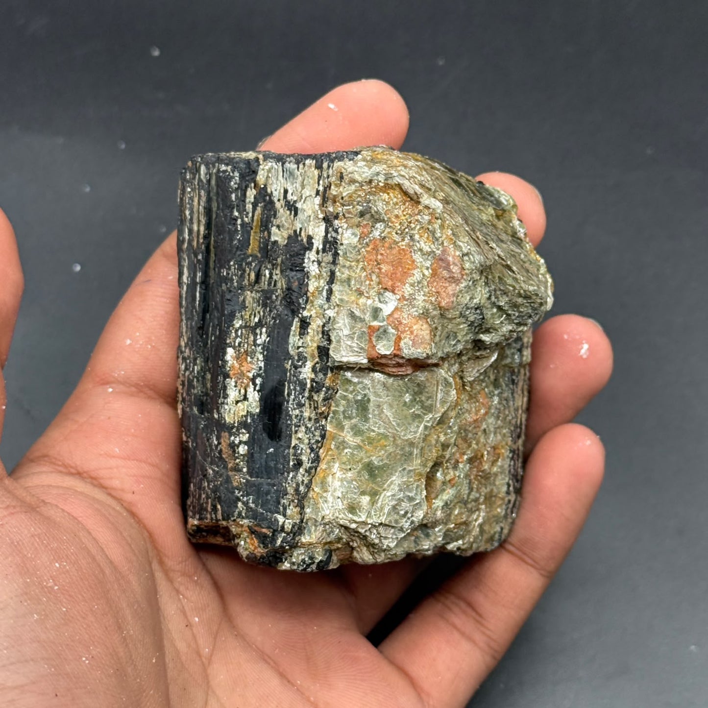 Close view of natural rough black tourmaline crystal with golden and orange areas