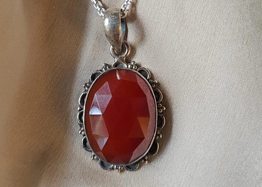 Necklace with a red pendant on a beige fabric background