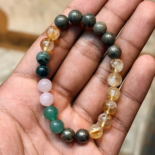 Confidence and Abundance combination bracelet beads held in hand with dark gray and golden citrine