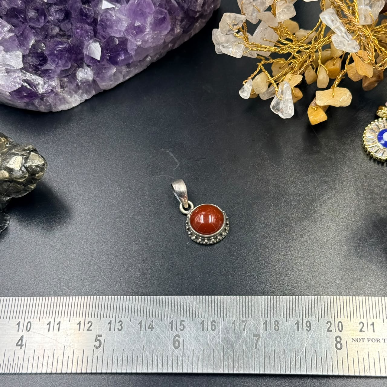 Carnelian 925 silver locket pendant with red oval gemstone, shown on black surface with ruler