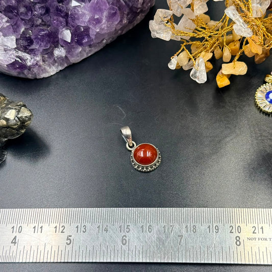 Carnelian 925 silver locket pendant with red oval gemstone, shown on black surface with ruler