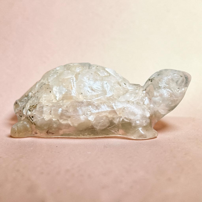Crystal quartz tortoise carving with textured shell surface, close-up on pink background