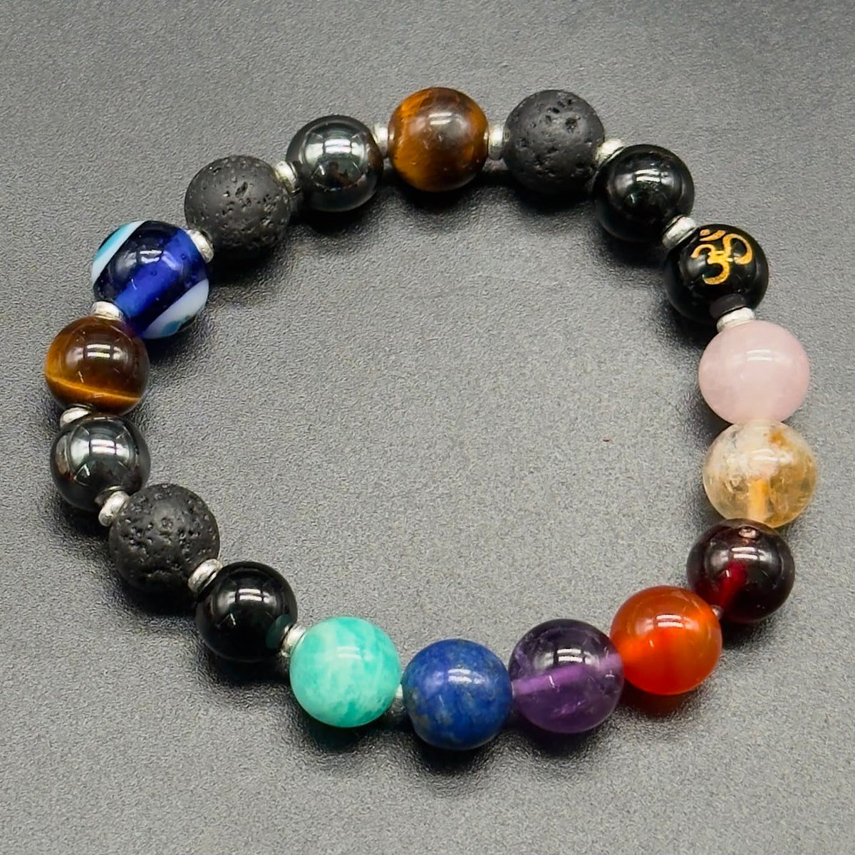 Divine Shield multi-gemstone beaded bracelet with evil eye and Om charm on grey background
