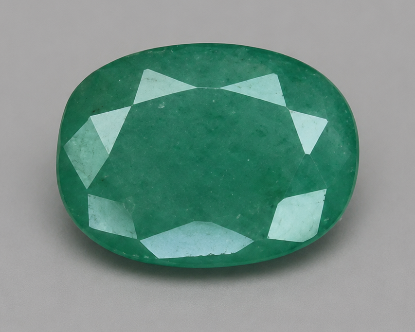 4.60-carat emerald gemstone oval cut with faceted crown on neutral background