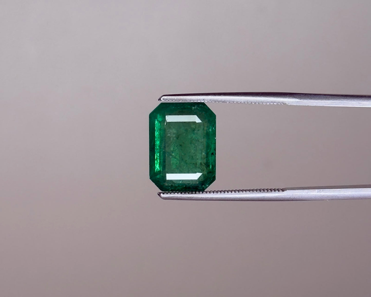 Emerald green emerald gemstone in an emerald-cut with prong set view