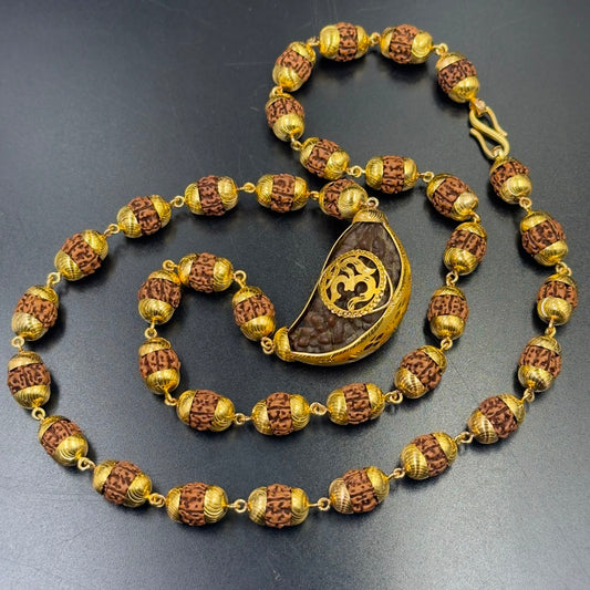 Gold-plated 925 silver rudraksha mala with Om pendant centerpiece on dark slate