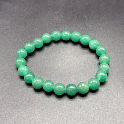 Green aventurine beaded bracelet with glossy round stones on gray background