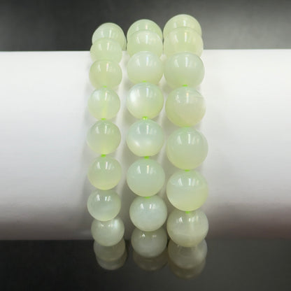 Close-up of green moonstone bracelet round beads reflecting light against a white background