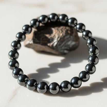 Hematite bracelet with 8mm round dark gray beads resting on a stone-like surface