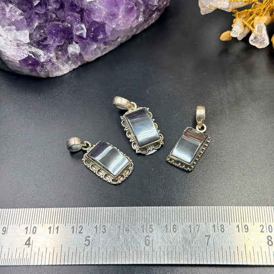 Hematite silver locket pendant and charm on black background with amethyst stone