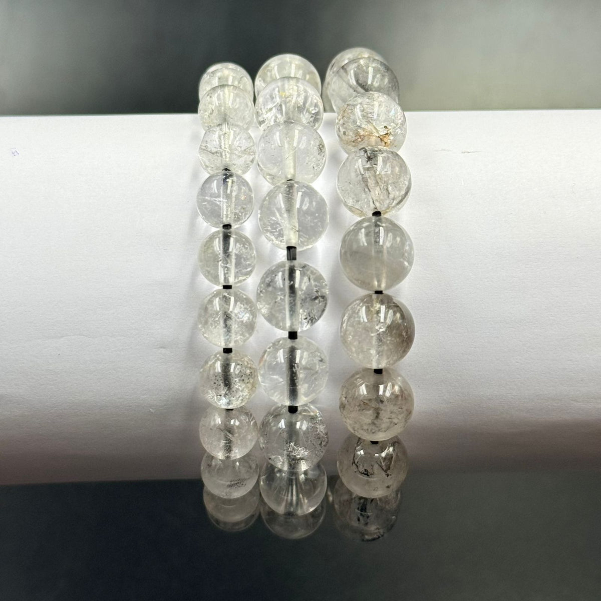 Herkimer Diamond bracelet beads close-up with clear faceted stones and reflections on a dark stand