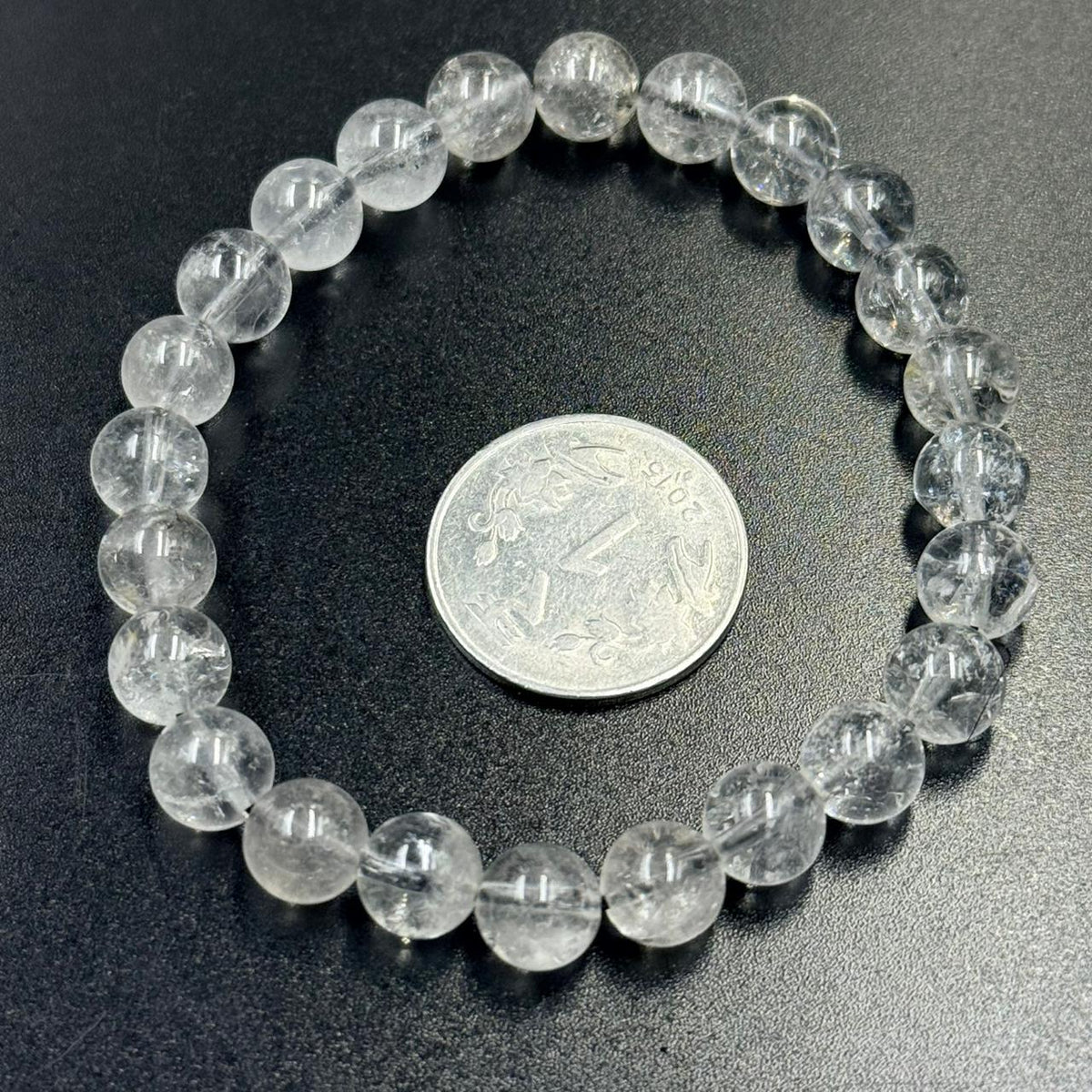 Herkimer Diamond bracelet on dark textured surface with a coin for size comparison