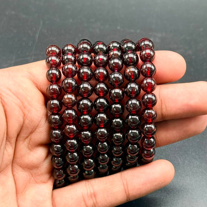 Close-up of Hessonite Garnet (Gomed) bracelet beads with deep reddish-brown 8mm polished round beads in hand