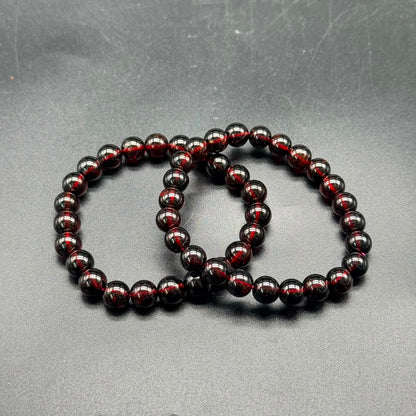 Hessonite Garnet (Gomed) stretch bracelet showing deep reddish-brown 8mm polished round beads on gray surface