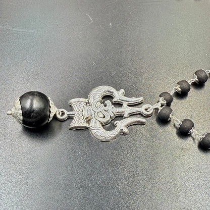 Karungali bead mala featuring Om Trishul metal pendant and black bead strand on grey surface