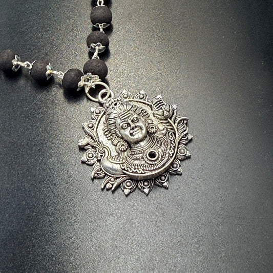 Karungali bead mala pendant with Lord Shiva face in metal on a dark textured background