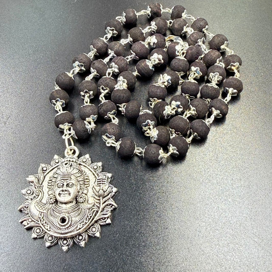 Karungali bead mala necklace with Lord Shiva face metal pendant shown on dark surface