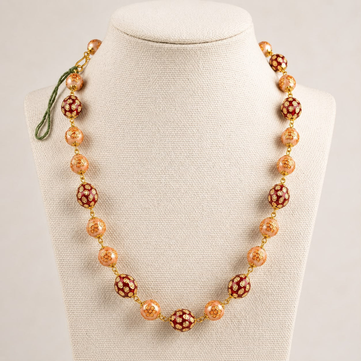 Kundan bead mala necklace with red and peach floral bead design on cream fabric display