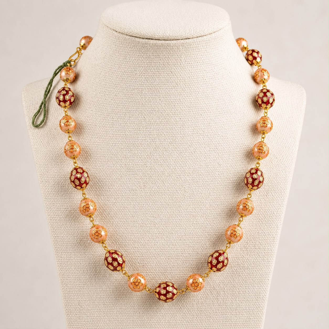 Kundan bead mala necklace with red and peach floral bead design on cream fabric display