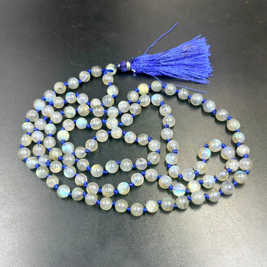 Labradorite mala beads with blue tassel shown laid on a dark surface