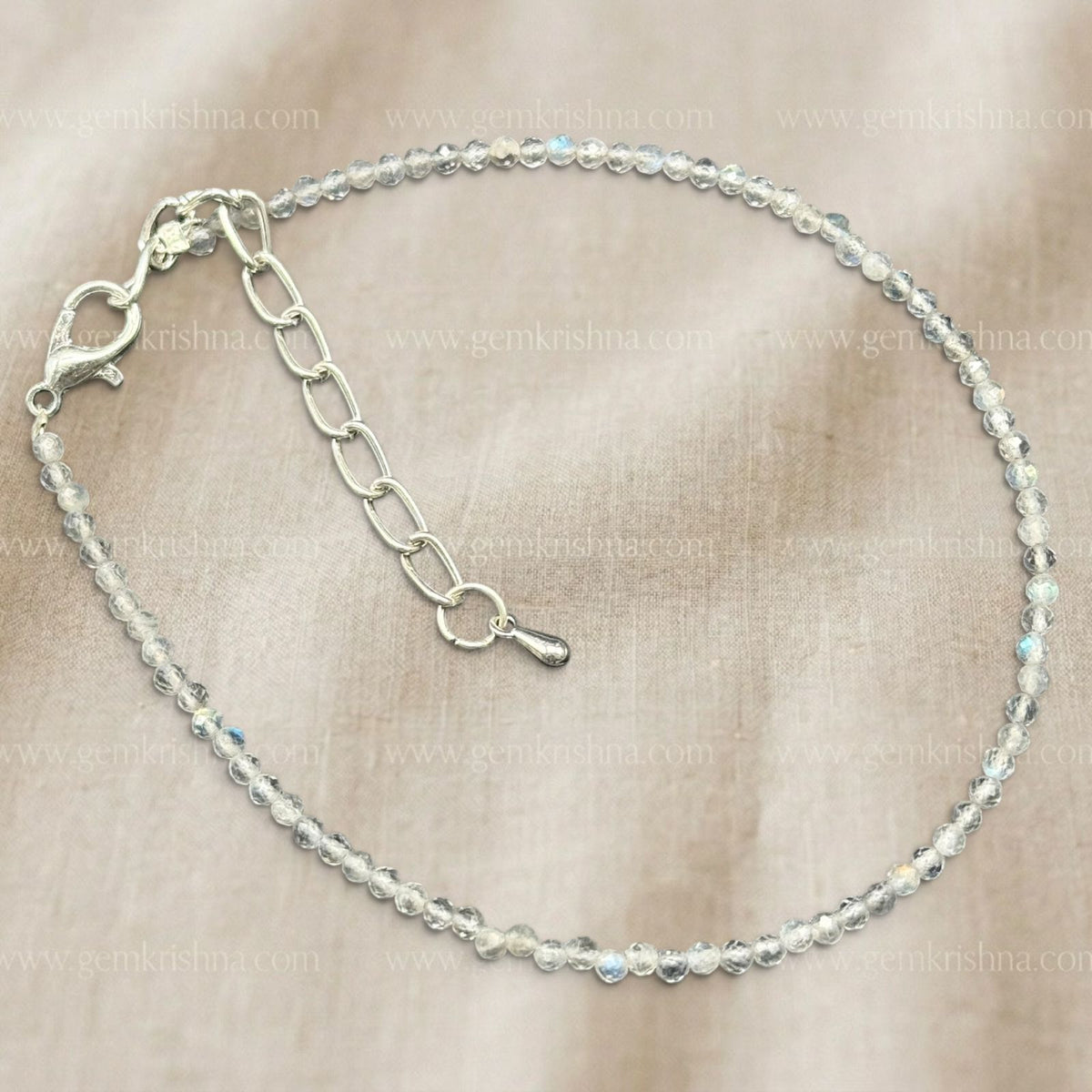 Labradorite anklet with round faceted beads and silver chain extender on beige background