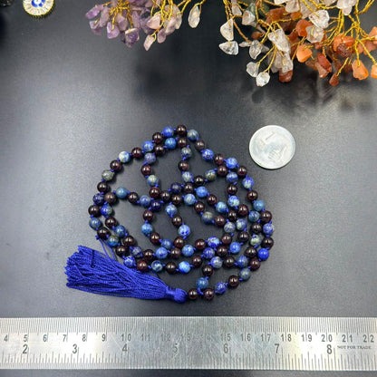 Lapis lazuli and garnet jaap mala beads with tassel laid on dark stone surface
