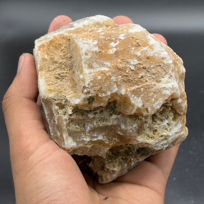 Large rough golden calcite chunk with textured crystal surface in hand
