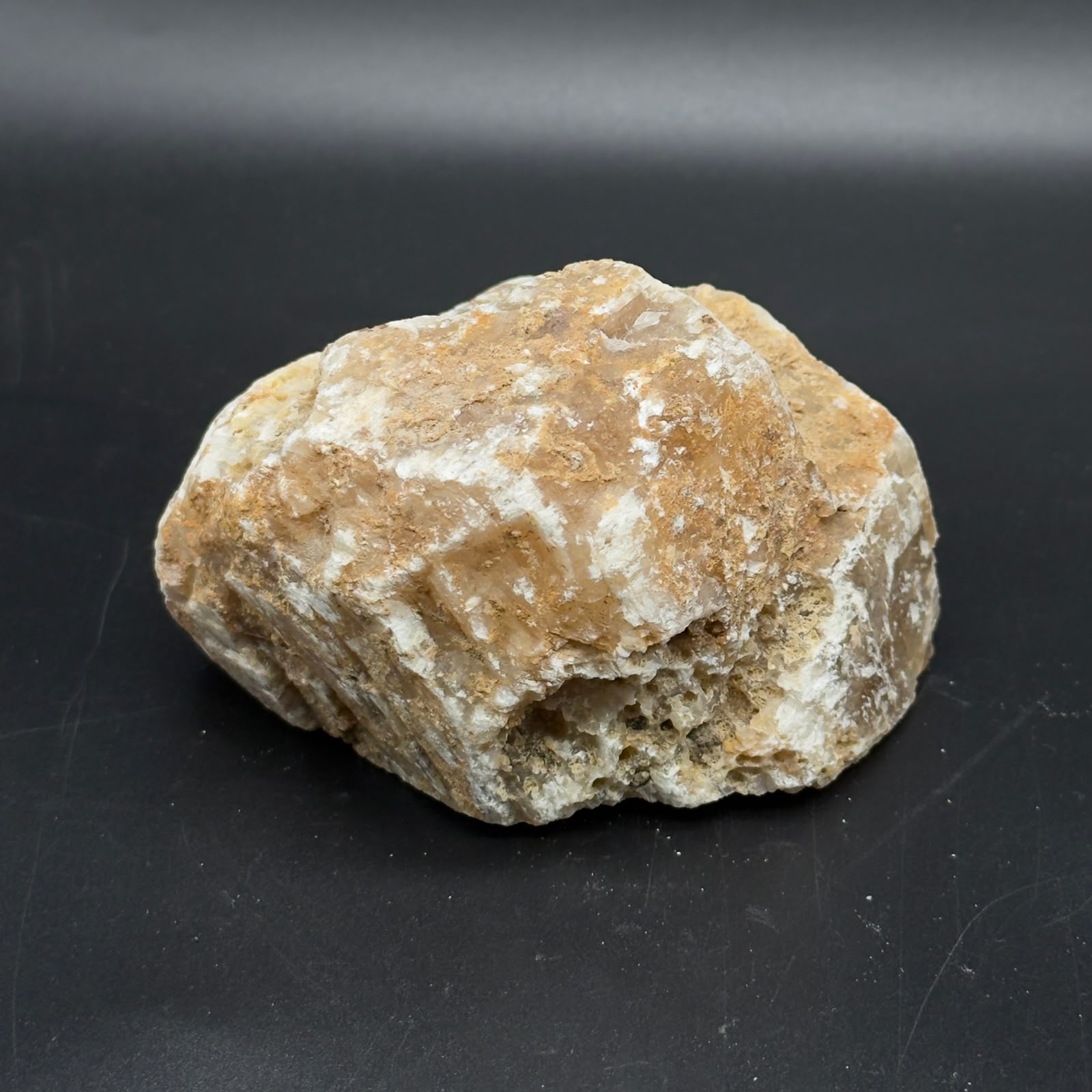 Large rough golden calcite crystal close-up on dark gray surface