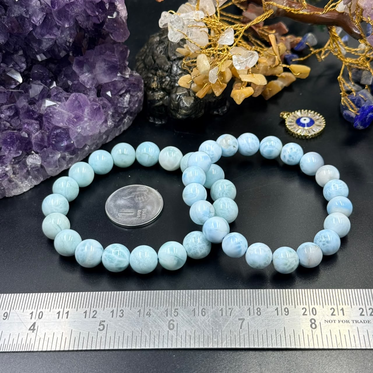 Larimar bracelet of round light blue beads laid on black surface with ruler for size