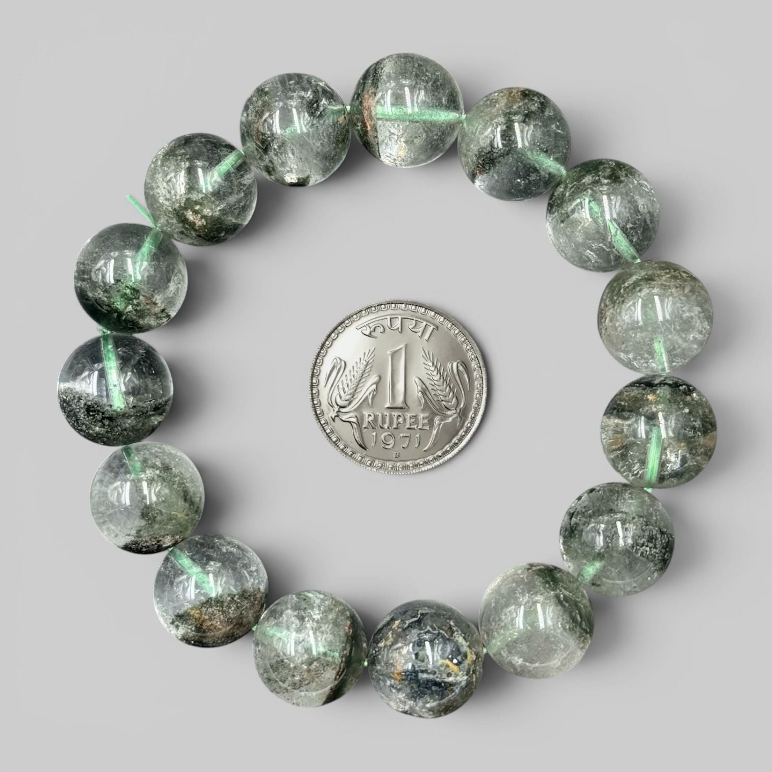 Lodolite Garden Quartz Phantom Quartz Bracelet with round beads arranged in a circle around an Indian 1 rupee coin on gray...