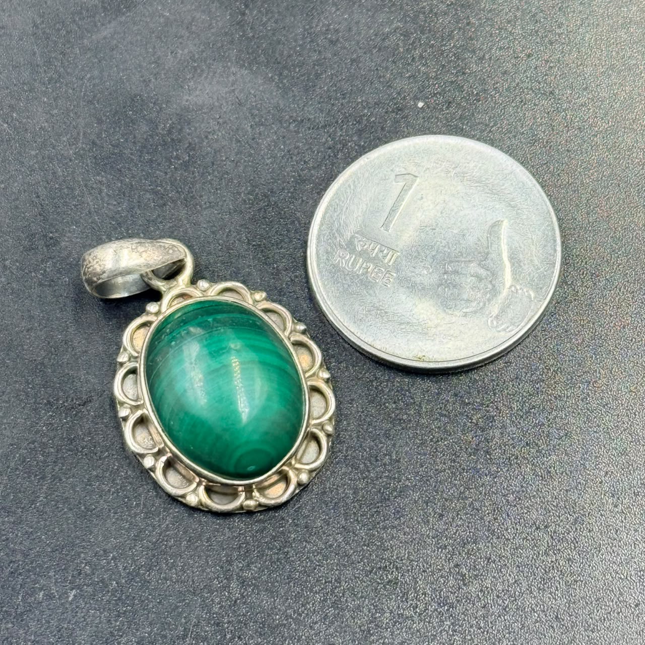 Malachite oval locket pendant in 925 silver setting on dark textured background