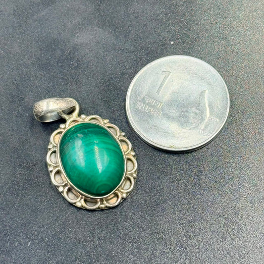 Malachite oval locket pendant in 925 silver setting on dark textured background