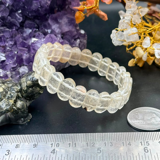 Milky quartz oval faceted flat bead bracelet on black surface with ruler for scale