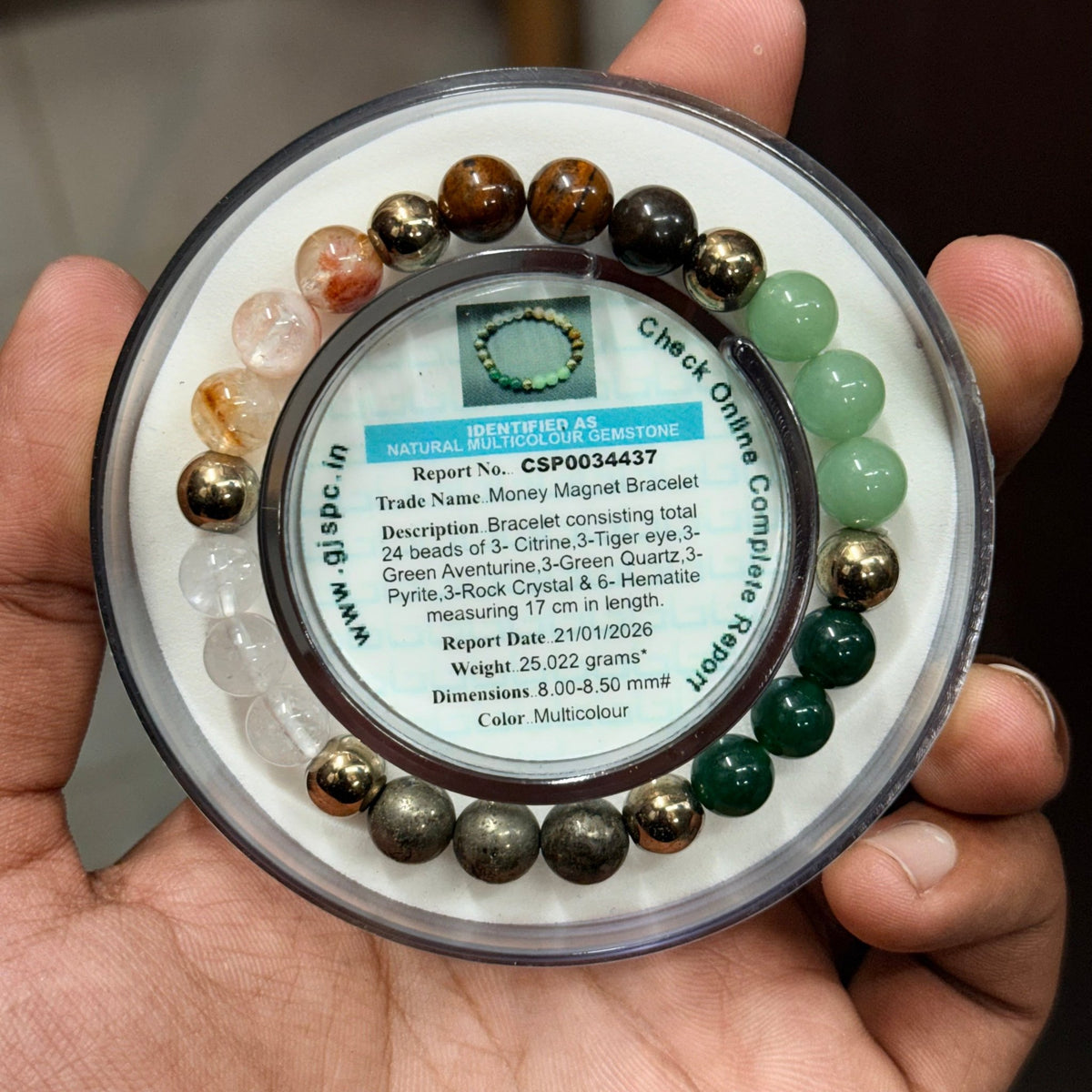 Close-up of natural money magnet bracelet beads on a labeled gemstone card in a hand