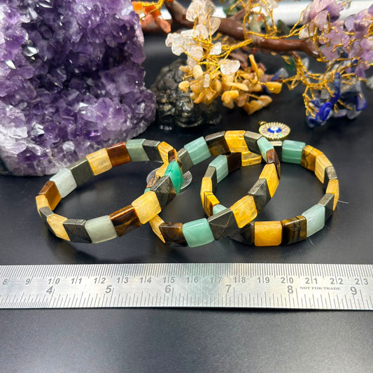 Money Magnet square bead bracelet with green, yellow, black and amber beads on a ruler
