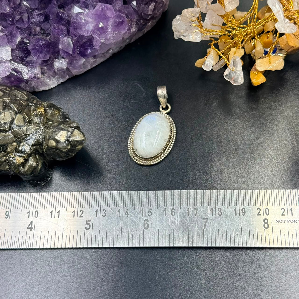 Moonstone oval locket pendant front view in 925 silver bezel setting on dark background