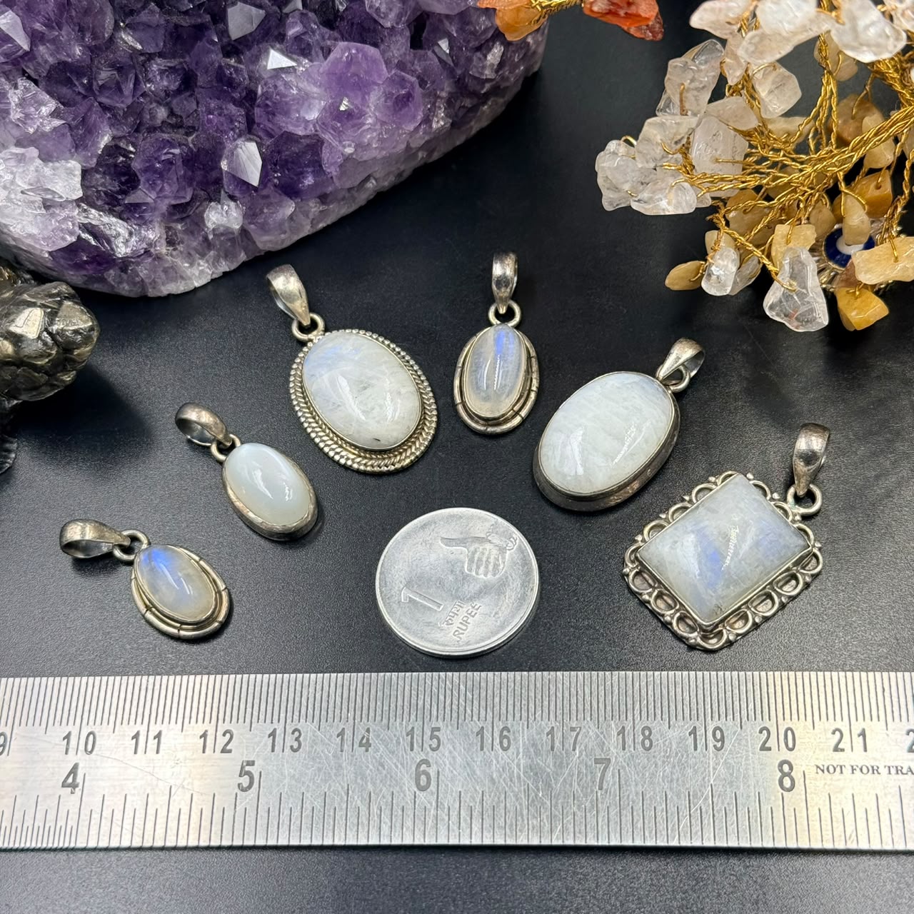 Moonstone oval locket pendant in 925 silver setting on dark stone with ruler for scale