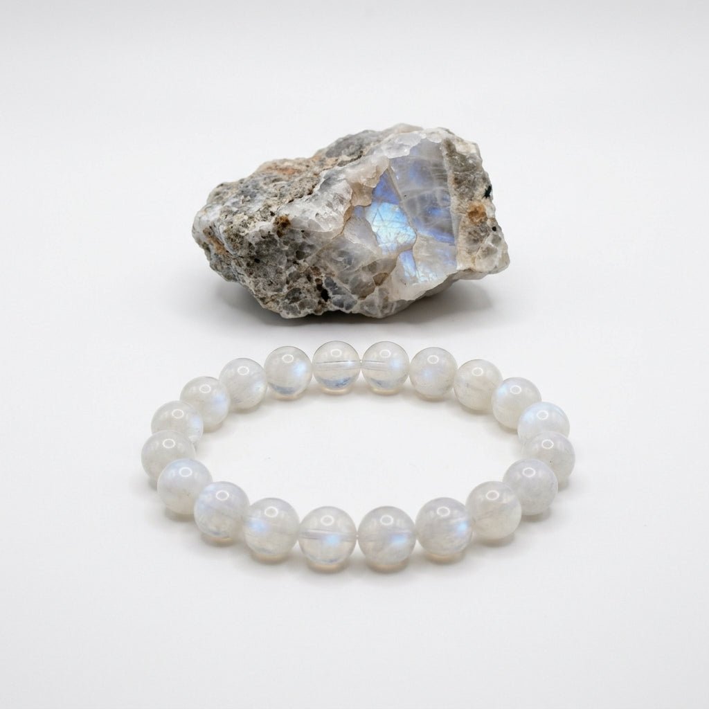 Moonstone bracelet with round beads and a natural moonstone rock specimen on white background