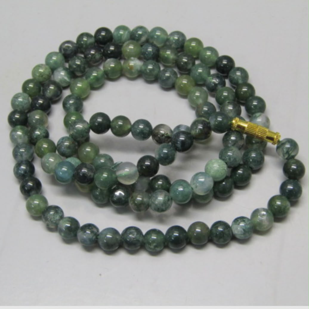 Close-up of moss agate mala bracelet-style strand with gold-toned clasp on white background